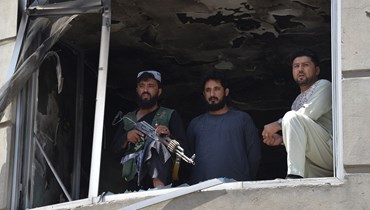 مقاتل من "طالبان" (يسار) ينظر من نافذة مدمّرة أثناء وقوفه حارساً في أعقاب هجوم مسلح على معبد للسيخ في كابول (18 حزيران 2022 - أ ف ب).