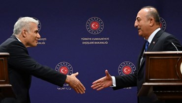 مصافحة بين تشاوش أوغلو (إلى اليمين) ولابيد خلال مؤتمر صحافي في أنقرة (23 حزيران 2022، أ ف ب).