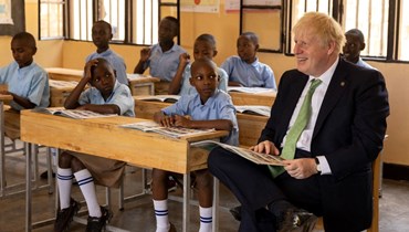 جونسون يتفاعل مع أطفال في الصف خلال زيارته مدرسة في كيغالي (23 حزيران 2022، أ ف ب).