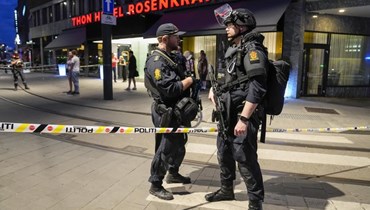 عناصر من الشرطة يقفون أمام حانة في وسط أوسلو (25 حزيران 2022، أ ب). 