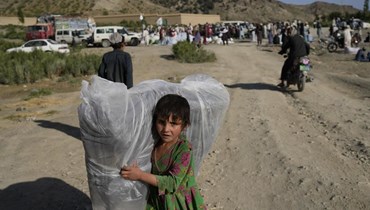 فتاة أفغانية تحمل فرشة تم التبرع بها بعد زلزال ضرب قرية غايان  في ولاية باكتيكا (24 حزيران 2022، أ ب). 