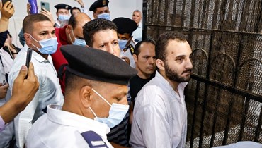 عادل (في الوسط) يحيط به الحراس في ختام أول جلسة محاكمة له في محكمة المنصورة شمال القاهرة (26 حزيران 2022، أ ف ب). 