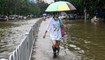 امرأة تمشي في شارع غمرته المياه بعد هطول أمطار غزيرة في شاوقوان بمقاطعة قوانغدونغ جنوب الصين (21 حزيران 2022، أ ف ب). 