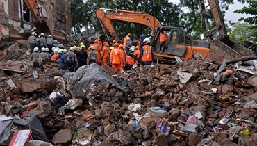 عمال إنقاذ يبحثون بين انقاض مبنى منهار في مومباي (28 حزيران 2022، أ ف ب). 