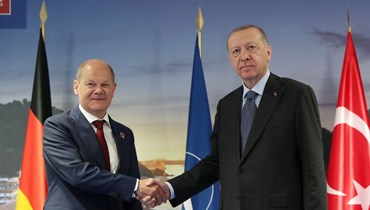 إردوغان (إلى اليمين) مصافحا شولتس قبل اجتماعهما على هامش قمة الناتو في مدريد (30 حزيران 2022، أ ف ب). 