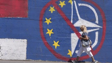 امرأة تمر قرب جدارية مناهضة للاتحاد الأوروبي وحلف الأطلسي في بلغراد (21 حزيران 2022، أ ب). 
