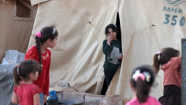 فتاة عند مدخل خيمة في "المخيم الأزرق" للسوريين النازحين قرب بلدة معرة مصرين في الجزء الشمالي من محافظة إدلب الشمالية الغربية (10 تموز 2022، أ ف ب). 