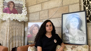 لينا أبو عاقله تجلس بين صور لعمتها الراحلة في منزل العائلة في القدس الشرقية المحتلة (13 تموز 2022، ا ف ب). 