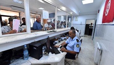 رجال شرطة الحدود التونسية يدققون في جوازات سفر اشخاص عند معبر طبرقة الحدودي الشمالي الغربي (15 تموز 2022، أ ف ب). 