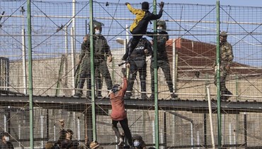 مهاجرون يتسلقون في مليلية السياج الفاصل بين جيب مليلية الإسباني والمغرب (24 حزيران 2022، أ ب). 