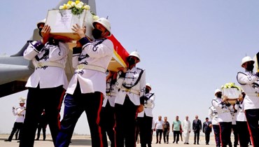 عناصر من حرس الشرف يحملون نعوش الضحايا لدى وصولها إلى مطار بغداد من أربيل (21 تموز 2022، أ ف ب). 