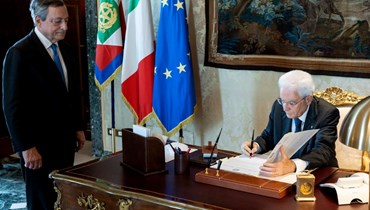 الرئيس الإيطالي سيرجيو ماتاريلا (إلى اليمين) يوقع المرسوم الخاص بحل البرلمان أمام رئيس الوزراء المستقيل ماريو دراغي (21 تموز 2022، ا ف ب). 