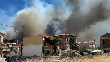 دخان يتصاعد فوق قرية فريسا في الجزء الجنوبي من جزيرة ليسبوس اليونانية، حيث اشتعلت النيران قرب منتجعات سياحية (24 تموز 2022، أ ف ب). 