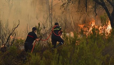 رجلا اطفاء يحاولان إخماد حرائق غابات في العرائش شمال المغرب (15 تموز 2022، أ ب). 