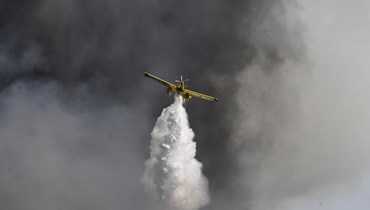 طائرة لمكافحة الحرائق تلقي بالمياه بالقرب من قرية كريستينا جنوب أولمبيا القديمة  جنوب غرب أثينا (24 تموز 2022، أ ف ب). 