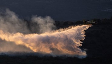 طائرة إطفاء تلقي بالمياه فوق غابات محترقة قرب فوغ في أرديش جنوب فرنسا (27 تموز 2022، أ ف ب). 