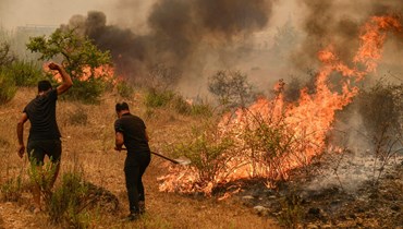 رجلا اطفاء يحاولان إخماد حرائق غابات في العرائش شمال المغرب (15 تموز 2022، أ ب).