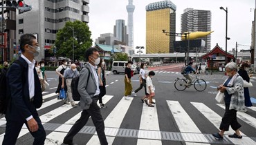اشخاص يعبرون الشارع في منطقة أساكوسا بطوكيو (4 آب 2022، أ ف ب). 