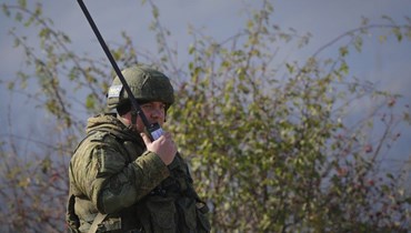 جندي حفظ سلام روسي يتحدث الى هاتف يعمل بالأقمار الاصطناعية عند نقطة تفتيش على الطريق إلى شوشا في منطقة ناغورنو- كراباخ (17 ت2 2020، أ ب). 
