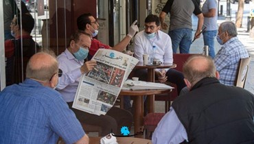 روّاد مقهى أحدهم يقرأ صحيفة "النهار" (نبيل إسماعيل).