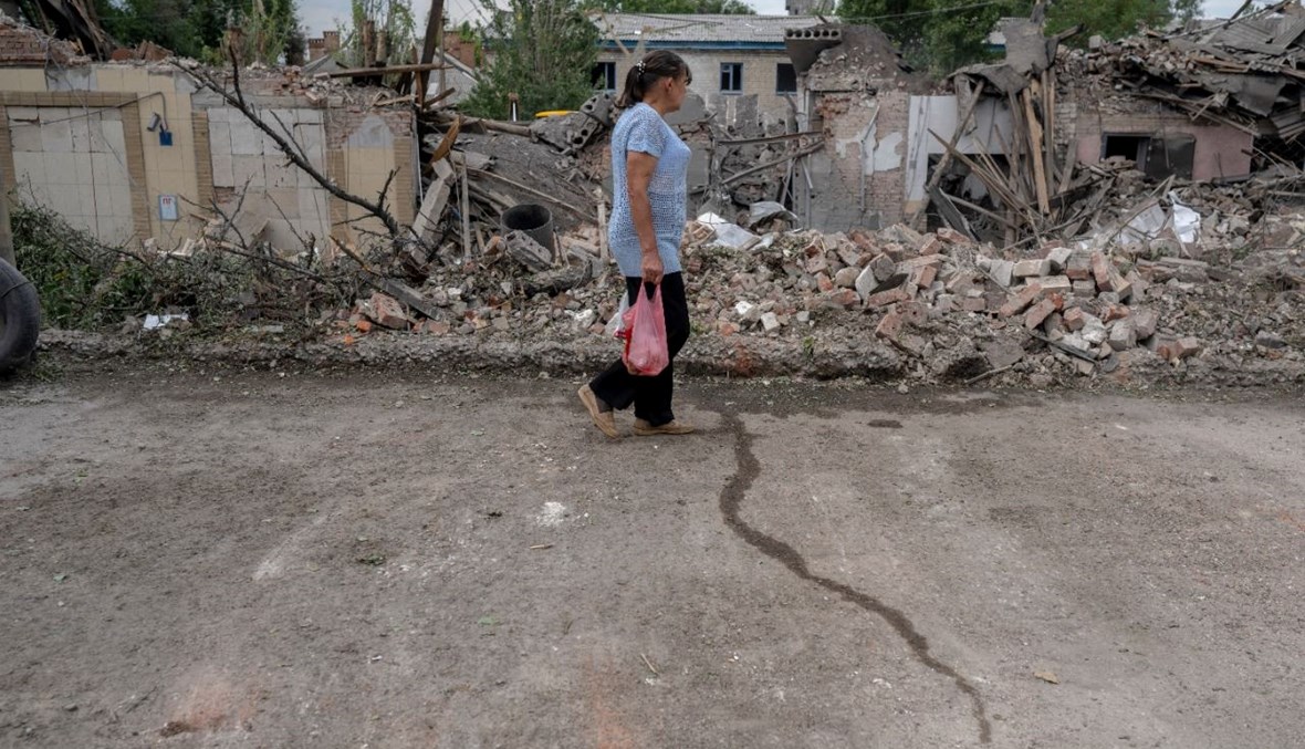 امرأة تمر قرب مبنى مدمر في توريتسك شرق أوكرانيا (5 آب 2022، أ ف ب).