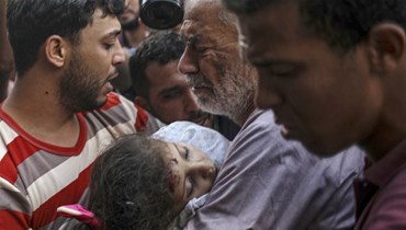 والد الطفلة علاء قدوم التي قُتلت في غارة إسرائيلية على غزة يحملها خلال مراسم تشييعها في غزة السبت (أ ف ب).