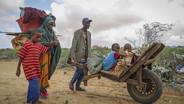 رجل مع أطفال وامرأة هاربين من مناطق منكوبة بسبب الجفاف، لدى وصولها إلى مخيم موقت للنازحين في ضواحي مقديشو (30 حزيران 2022، أ ب). 