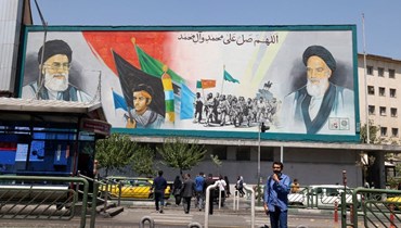 إيرانيون يمرون قرب لوحة اعلانية تحمل صورتي الخميني وخامنئي في طهران (13 آب 2022، أ ف ب). 