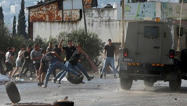 شبان فلسطينيون يرشقون سيارات للجيش الاسرائيلي بالحجارة خلال عملية عسكرية لاعتقال مطلوبين من مخيم بلاطة قرب نابلس بالضفة الغربية (17 آب 2022، أ ف ب). 