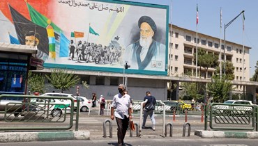 إيرانيون يمرون قرب لوحة اعلانية عليها صورة الخميني في طهران (13 آب 2022، أ ف ب). 