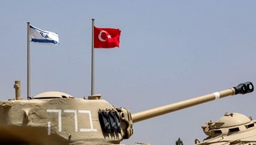 أعلام إسرائيل وتركيا خلف دبابة قتال من طراز M4A1 (أ ف ب). 