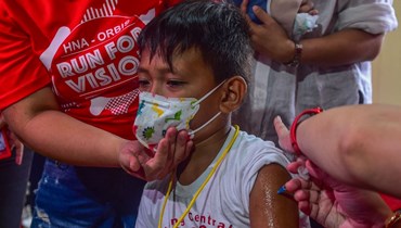 طالب يتلقى جرعة معززة من لقاح كورونا في مدرسة سان خوان الابتدائية في سان خوان بضواحي مانيلا (22 آب 2022، أ ف ب).