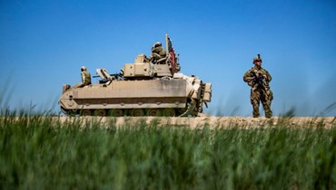 جندي أميركي يقف بجانب مركبة برادلي القتالية الأميركية خلال دورية في ريف القامشلي في محافظة الحسكة شمال شرق سوريا (20 آب 2022، أ ف ب). 