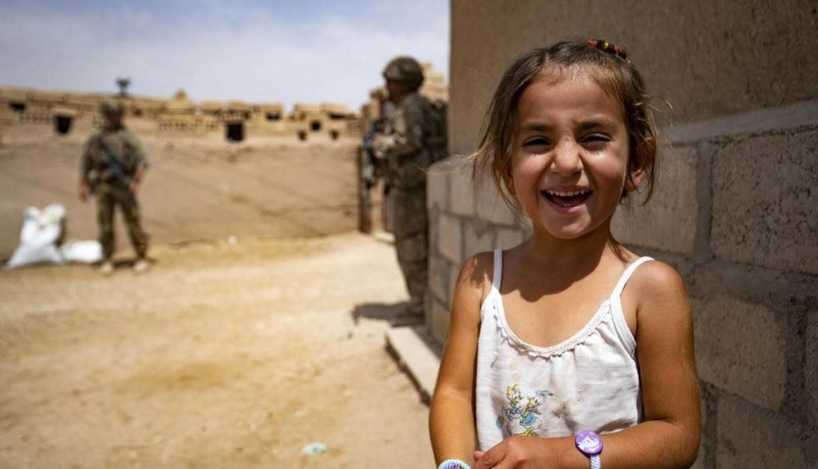 طفلة سورية أمام عناصر من القوات الأميركية عند الحدود السورية التركية (أ ف ب).