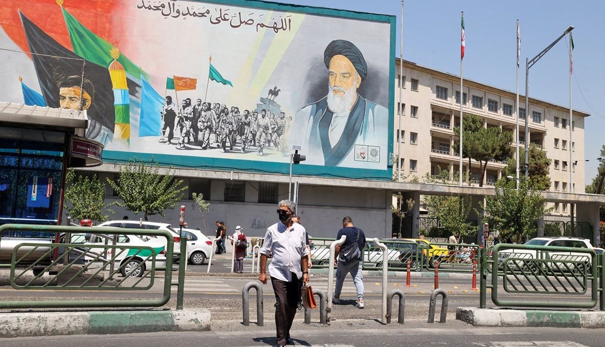 إيرانيون يمشون أمام لوحة إعلانية تحمل صورة المرشد الأعلى الراحل آية الله روح الله الخميني في العاصمة طهران (13 آب 2022 - أ ف ب).