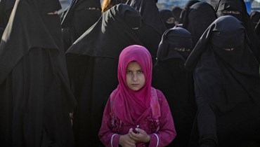 طفلة محاطة بعدد من النساء في مخيّم "الهول"، الذي يديره الأكراد ويحتجز أقارب مقاتلين من تنظيم "داعش" في شمال شرق الحسكة (أ ف ب).