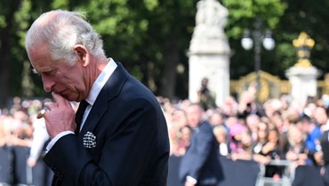ملك بريطانيا تشارلز الثالث يلقي نظرة على الأزهار التي تركت خارج قصر باكنغهام في لندن (9 أيلول 2022، أ ف ب). 
