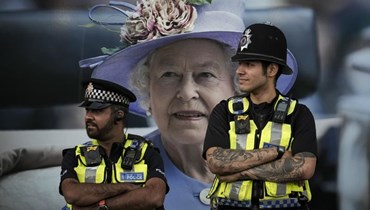 شرطيان بريطانيان وخلفهما صورة كبيرة للملكة الراحلة إليزابيث الثانية - "أ ب"