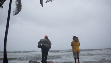 رجال ينظرون إلى البحر خلال وقوفهم على الشاطئ في ناغوا بجمهورية الدومينيكان اثناء مرور الإعصار فيونا (19 أيلول 2022، أ ف ب). 