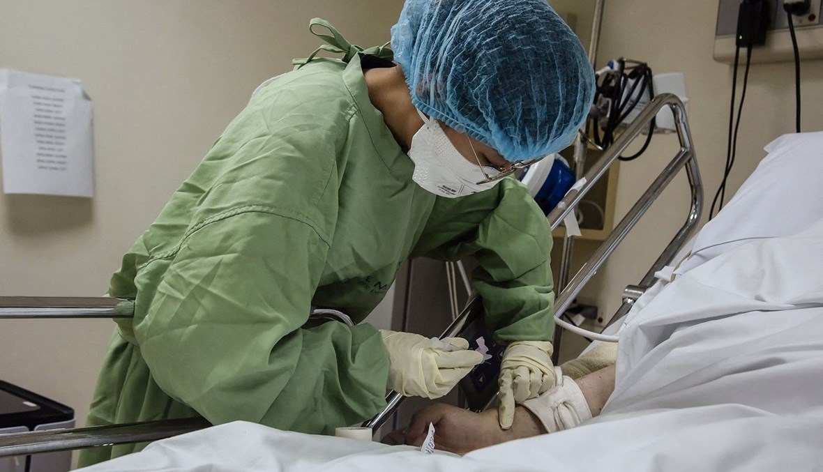 ممرضة تعالج مريضاً من كوفيد-19 داخل وحدة العناية المركزة في مستشفى في مانيلا (16 أيلول 2022 - أ ف ب).