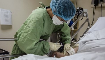 ممرضة تعالج مريضاً من كوفيد-19 داخل وحدة العناية المركزة في مستشفى في مانيلا (16 أيلول 2022 - أ ف ب).