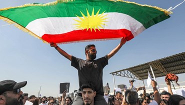 رجل يلوح بالعلم الكردي خلال مظاهرة تندد بوفاة مهسا أميني في أربيل، عاصمة إقليم كردستان العراق (24 أيلول 2022 - أ ف ب).