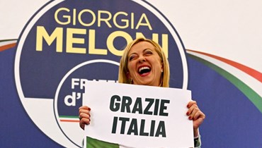 ميلوني ضاحكة بينما حملت لافتة كتب عليها "شكرًا لك إيطاليا" بعدما ألقت خطابًا في مقر حملتها الانتخابية ليلة 26 أيلول 2022 في روما، بعد تصويت البلاد في انتخابات تشريعية (أ ف ب). 