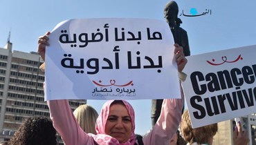 مريضة سرطان تحمل لافتة بمطالبها خلال المسيرة (حسام شبارو).