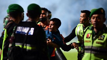 صبي محمولا بعدما أمّن عناصر من الجيش الإندونيسي الملعب بعد مباراة كرة القدم في مالانغ بجاوة الشرقية (1 ت1 2022، أ ف ب).