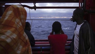 صورة ارشيفية- مهاجرون ينظرون إلى الساحل الإيطالي من على متن سفينة "اوشن فايكينغ" بينما تقترب من ميناء ميسينا الصقلي   بجنوب إيطاليا (24 أيلول 2019، أ ب). 