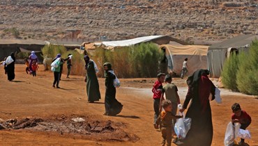 سوريون يحملون مواد تنظيف وزعتها منظمة غير ربحية في مخيم للنازحين في بلدة سرمدا بمحافظة إدلب شمال غرب سوريا (25 أيلول 2022، أ ف ب). 