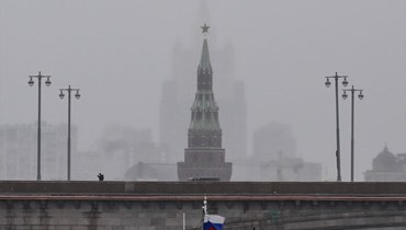 شخص يمشي على جسر فوق نهر موسكفا قرب برج فودوفزفودنايا في الكرملين ومقر وزارة الخارجية الروسية (في الخلفية) وسط موسكو (4 ت1 2022، أ ف ب). 
