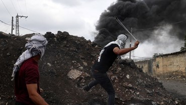 متظاهر فلسطيني يقذف الحجارة خلال اشتباكات مع جنود إسرائيليين في أعقاب تظاهرة ضد مصادرة إسرائيل للأراضي الفلسطينية في قرية كفر قدوم بالضفة الغربية المحتلة (7 ت1 2022، أ ف ب).