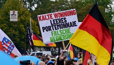 متظاهر يحمل لافتة كتب عليها "شقة باردة، محفظة فارغة، حكومة خاطئة" خلال المسيرة اليمينية المتطرّفة في برلين (8 ت1 2022 - أ ف ب).